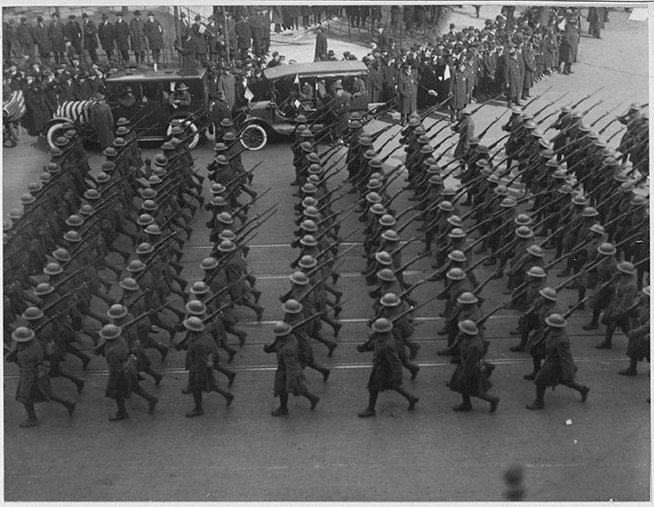 Strict lines of soldiers marching in rhythm in the street.